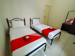 two beds with red and white sheets in a room at D' Anjung Inn in Tangkak