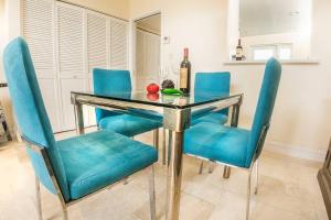 a dining room table with blue chairs and a bottle of wine at Villa at St. James Place “H”, Luxury, Pet Friendly in Miami