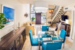 a living room with a glass table and blue chairs at Villa at St. James Place “H”, Luxury, Pet Friendly in Miami