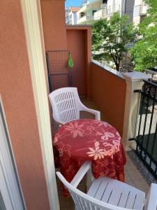 un balcone con 2 sedie bianche e un tavolo rosso di Via Modena a Cattolica