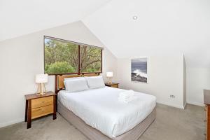 a white bedroom with a large bed and a window at Goanna Cottage - Woodstone Estate in Dunsborough