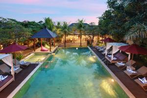 una vista aérea de una piscina con sillas y sombrillas en Lumbini Luxury Villas and Spa en Jimbaran