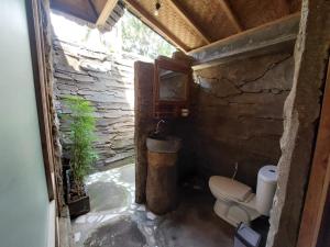 a bathroom with a toilet and a stone wall at Segara Urip in Negara