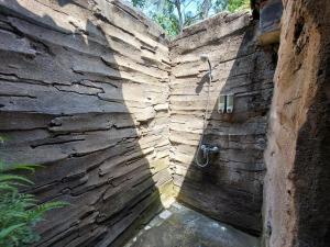 y baño con ducha en una pared de piedra. en Segara Urip, en Negara