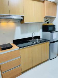 cocina con fregadero y nevera en Studio Apartment with pool and gym by The Cusicks, en Davao City