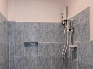 a shower in a bathroom with gray tiles at Palmera El Nido Inn in El Nido