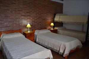 a bedroom with two beds and a brick wall at Duplex de la Virgen in Mina Clavero