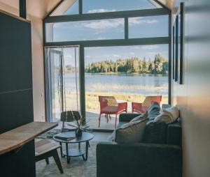 a living room with a couch and a view of a lake at PullanHouse Laima - small and cosy lakeside holiday house in Alūksne +10 photos