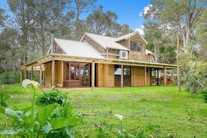 ein Holzhaus auf einem Feld mit einem Rasenplatz in der Unterkunft Kookaburra Cottage at Woodstone Estate in Dunsborough