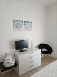 a bedroom with a white dresser with a tv and a chair at CASA Chloe' in Lido di Jesolo