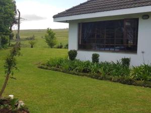 a white house with a window and a yard at Paradise View Guesthouse in Graskop