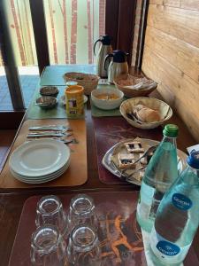 Agriturismo Altana Del Motto Rosso في Gattico: طاولة بها صحون واكواب وزجاجات ماء