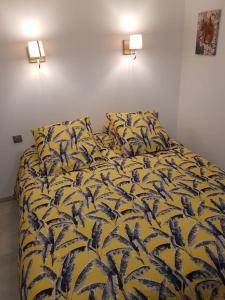 uma cama com um edredão amarelo com pássaros em Le petit écureuil em Saint-Saturnin-dʼApt