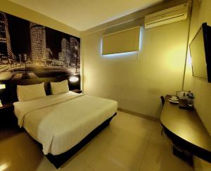 a hotel room with a bed and a desk at Hotel Sampurna Cirebon in Cirebon