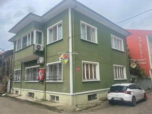 una casa verde con un coche aparcado delante de ella en Limon Pansiyon, en Edirne