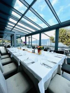 una mesa larga con mesas blancas y sillas en una habitación con ventanas en Albergo Del Sole, en Porto Valtravaglia