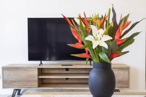 a black vase with flowers in front of a tv at Lifestyle Rich Waterfront Residence with Bay Views in Larrakeyah