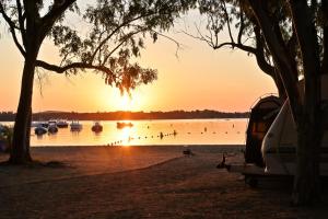 a camper parked on the shore of a lake with boats at CAMPING LES ILOTS D'OR in Porto-Vecchio