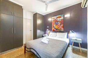a bedroom with a bed and a painting on the wall at Artistic City Escape with Balcony and Parking in Darwin
