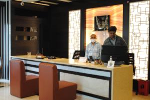 two men standing at a counter with a laptop at Mysore Royale in Mysore