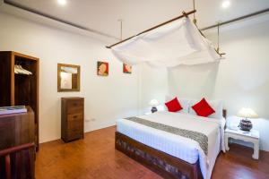 a bedroom with a white bed with red pillows at Laksasubha Hua Hin in Hua Hin