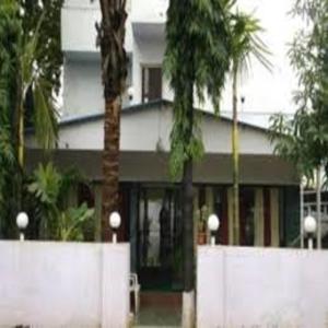um edifício branco com palmeiras em frente em Hotel Geetanjali St Bus Stand Panvel em Panvel