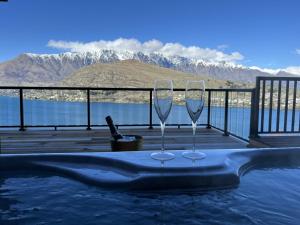 due bicchieri da vino seduti su un tavolo accanto alla piscina di Spa, Mountains & Lake a Queenstown