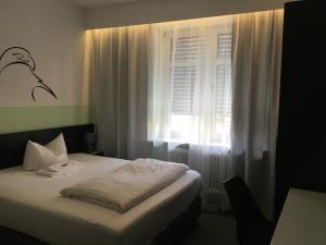 a bedroom with a bed and a window with white curtains at Hotel Augsburg Goldener Falke in Augsburg +15 photos