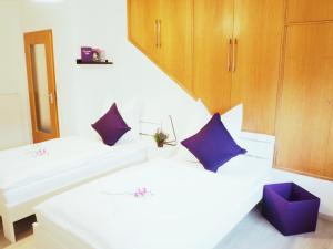 2 Betten in einem Zimmer mit lila Kissen in der Unterkunft Villa Natur Ferienwohnung & Monteurwohnung in Mühlhausen