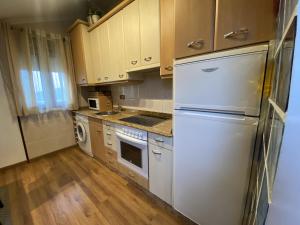 una cocina con electrodomésticos blancos y armarios de madera en usgo beach apartment, en Miengo