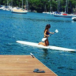 Una donna su una tavola da paddle in acqua di Tides Reach Boathouse water-access-only a Church Point Altre 25 foto