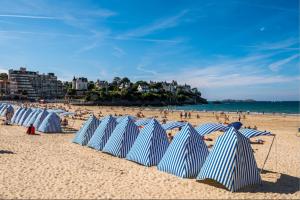 a group of blue and white umbrellas on a beach at Dinard: studio à 100 m de la plage de L'Ecluse in Dinard