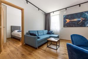 ein Wohnzimmer mit einem blauen Sofa und einem Spiegel in der Unterkunft Vanagupes Park Apartments, By Cohost in Palanga