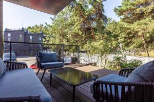 eine Terrasse mit Stühlen und einem Tisch auf einer Terrasse in der Unterkunft Vanagupes Park Apartments, By Cohost in Palanga