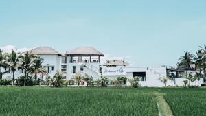 a large white building with a field in front of it at Swell Hotel, Pool Bar & Restaurant in Tanah Lot