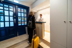 a woman standing at a counter with a yellow suitcase at Hotel&Spa El Puerto in Mundaka