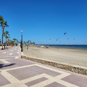 a beach with palm trees and people on the beach at Geweldig Appartement in Los Alcázares direct aan de Boulevard in Los Alcázares