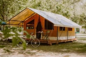 ein Zelt mit Fahrrad im Gras geparkt in der Unterkunft CAMPING ONLYCAMP LES VAILHES in Lodève