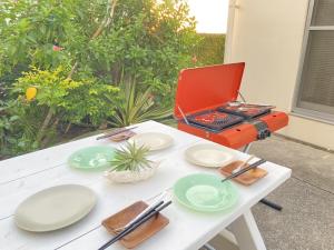 a table with plates and a red laptop on it at 無料ビーチまで3分!BBQとホームシアターが楽しめるファミリー向け宿 Fujiyama Terrace in Yomitan