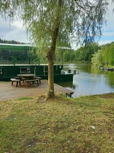 a picnic table and a boat on a river at le bateau sur lac privé de 2 hectares poissonneux au milieu des bois in Florennes