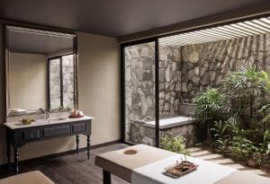 a bathroom with a sink and a stone wall at Cinnamon Bentota Beach - Signature Selection in Bentota