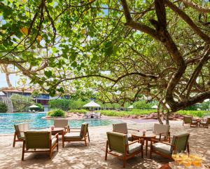 a group of tables and chairs next to a pool at Cinnamon Bentota Beach - Signature Selection in Bentota