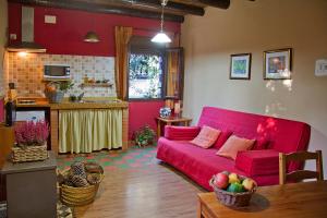 een woonkamer met een rode bank en een keuken bij Finca la Colorá in Fuenteheridos