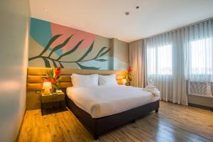 um quarto com uma cama grande e uma pintura na parede em 1521 Hotel & Spa em Mactan
