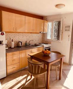 eine Küche mit Holzschränken und einem Tisch mit einer Schüssel Orangen darauf in der Unterkunft Zacharos Elegant Studio in Leonidi