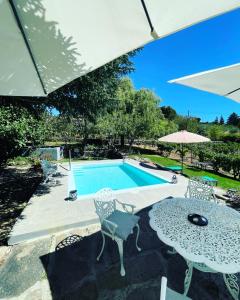 a pool with a table and chairs and an umbrella at Casa do Beco B&B Douro - Guest House in Parambos