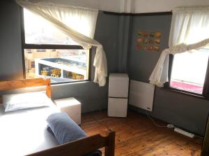 1 dormitorio con 1 cama y 2 ventanas en African Soul Surfer, en Muizenberg