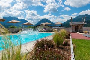 a resort swimming pool with mountains in the background at Tierwarthof in Fieberbrunn