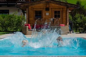 dos niños jugando en una fuente en una piscina en Tierwarthof, en Fieberbrunn