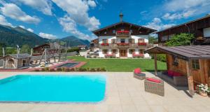 a villa with a swimming pool in front of a house at Tierwarthof in Fieberbrunn